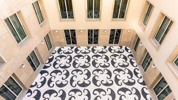 A high-ceiling atrium with a patterned floor, multiple windows, and a central open space.
