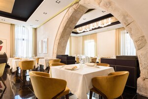 A restaurant with round tables, yellow chairs, and stone arches.