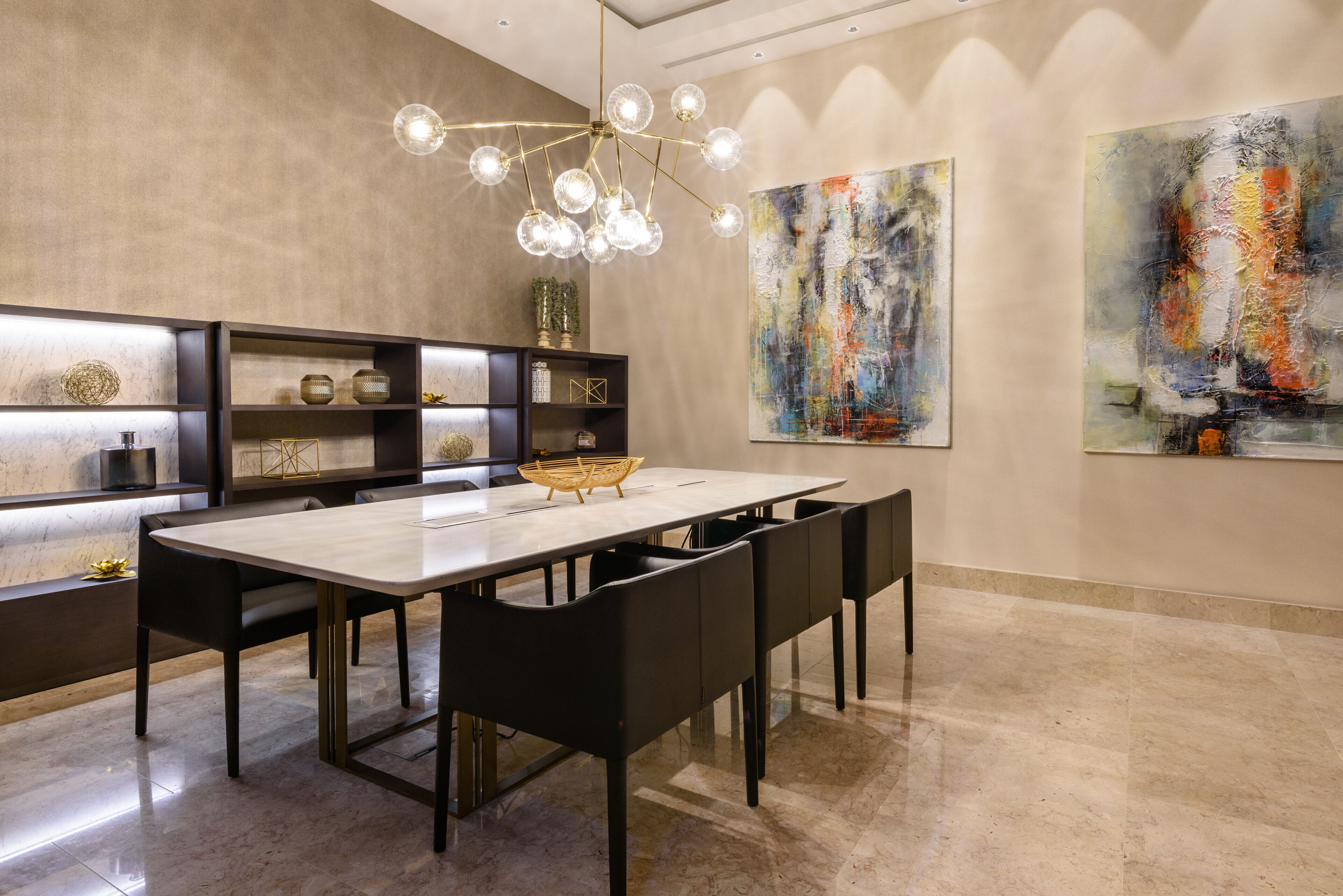 A modern dining area with a marble table, black chairs, and a unique chandelier.
