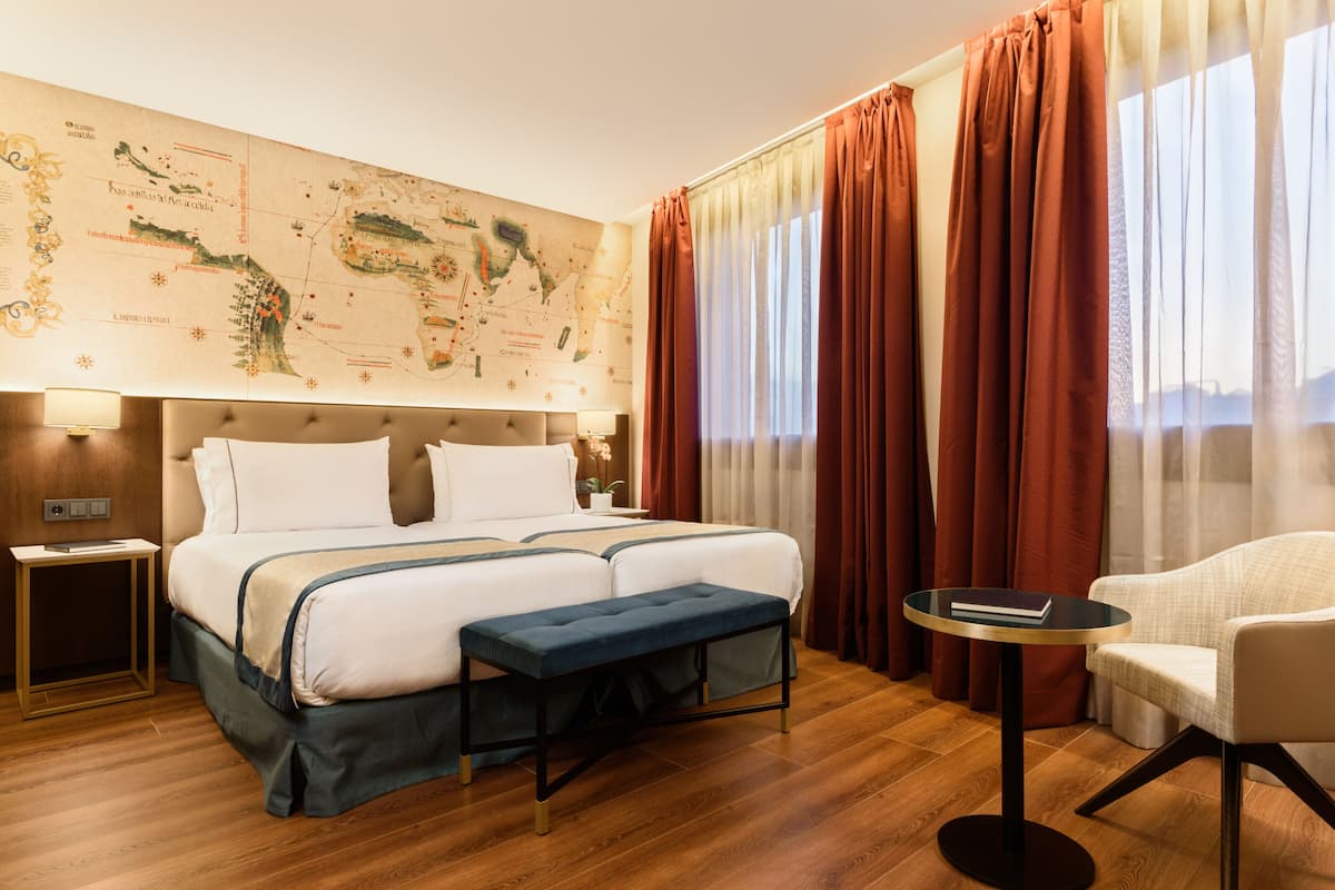 Een hotelkamer met een groot bed, een klein rond tafeltje, een stoel en een kaart aan de muur.