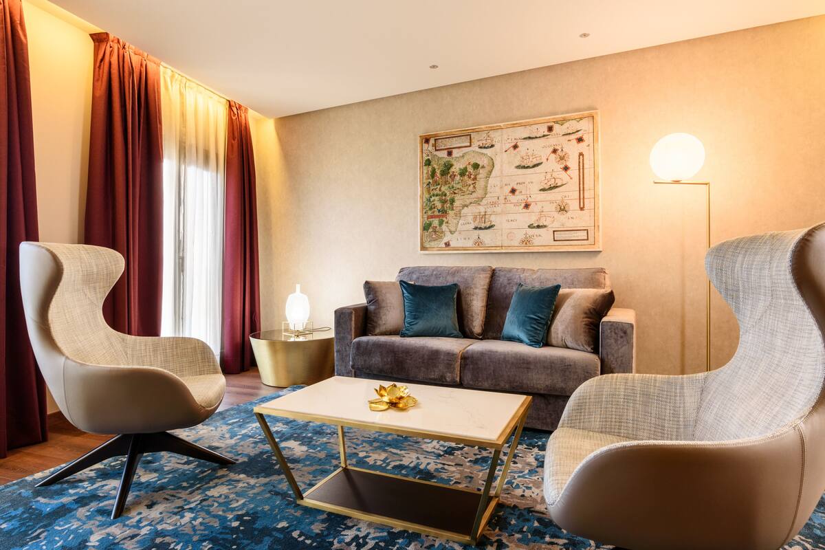 Een moderne woonkamer met een bank, twee fauteuils, een salontafel en een kaart aan de muur.