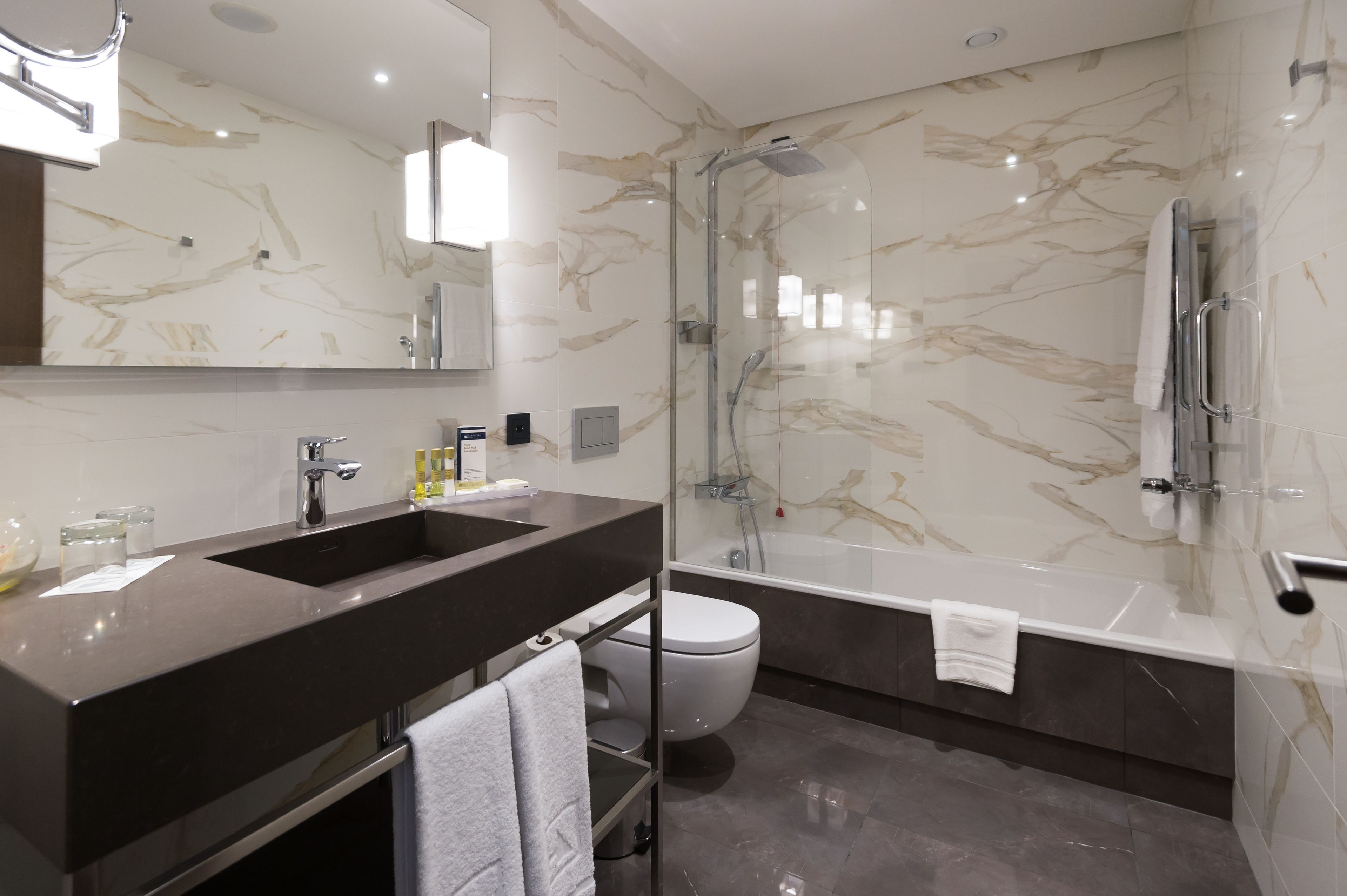 Un baño moderno con lavamanos doble, ducha con cerramiento de vidrio y un inodoro separado.