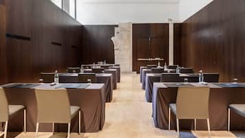 A conference room with multiple tables and chairs, a stone column, and wooden walls.