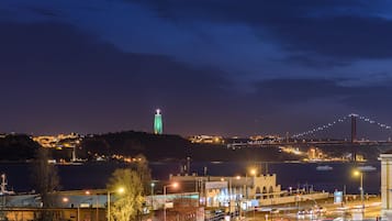 A nighttime cityscape with a prominent bridge and a lit tower.
