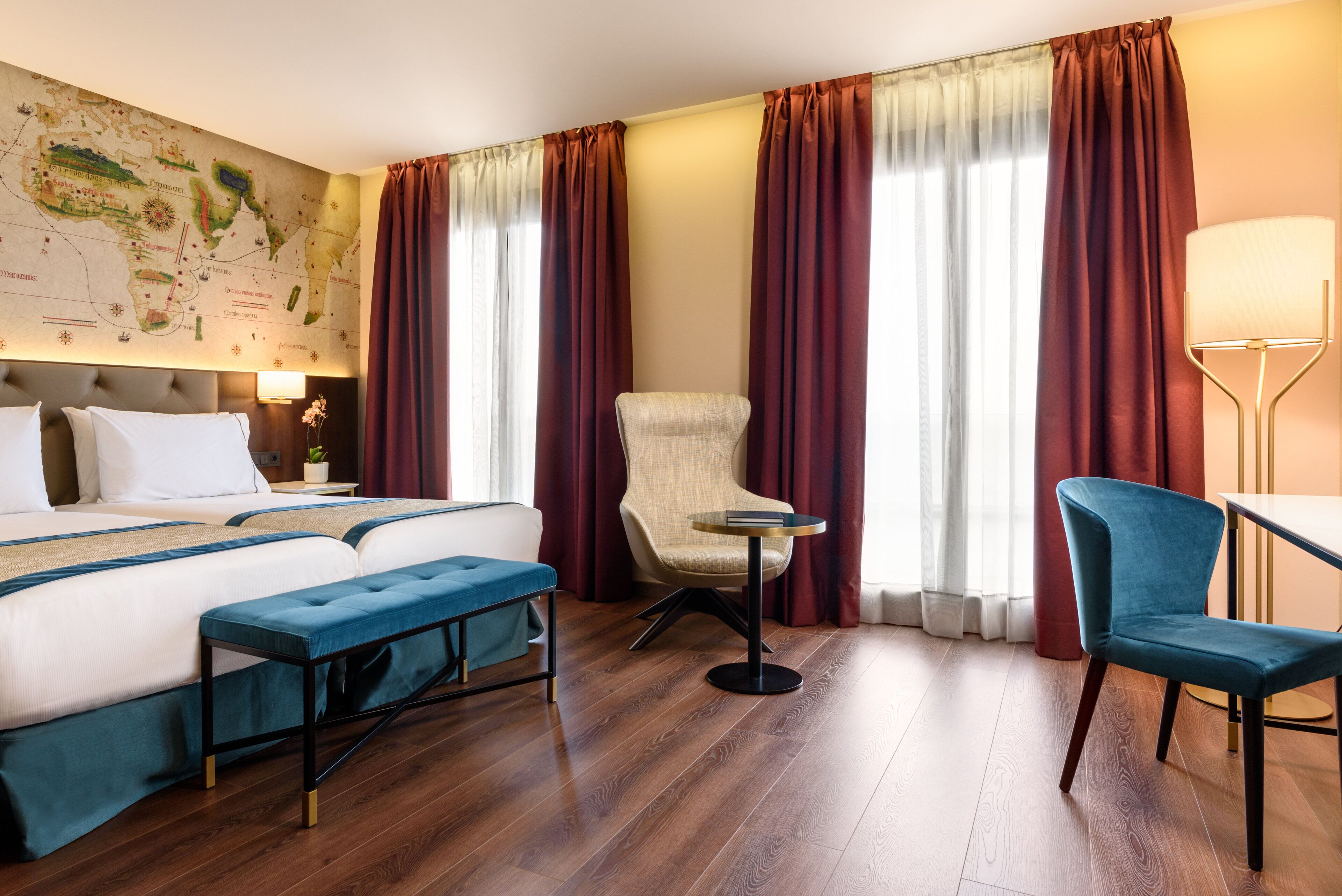 Une chambre d’hôtel avec un grand lit, deux chaises, une petite table et une carte accrochée au mur.