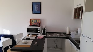 Une cuisine compacte équipée d’un four à micro-ondes, d’une cuisinière et d’un petit coin repas avec des chaises et une table.