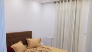 Une chambre à coucher avec un lit, un radiateur et un rideau.