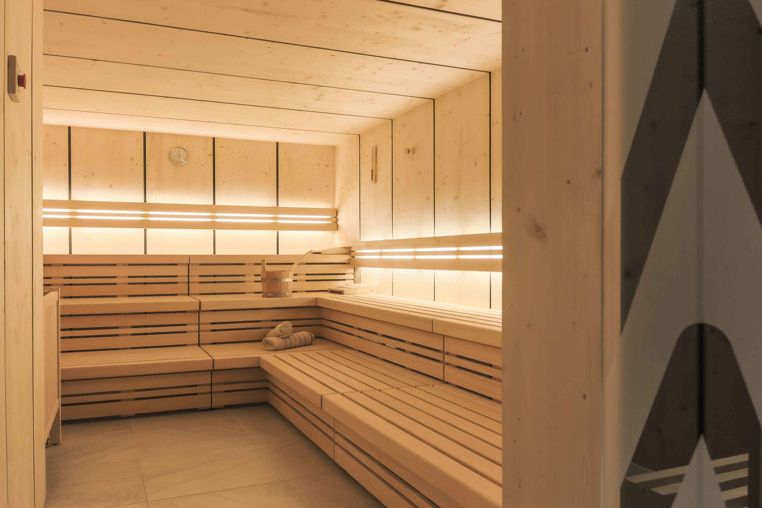 Un sauna avec des bancs en bois, un plafond en bois et un mur orné d’une horloge.