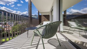 En balkon med udsigt til bjerge, en stol og et bord.