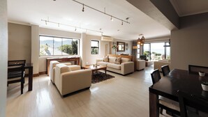 A spacious living room with a large dining table, sofas, and a view of the outdoors. - Whale Away Guest House (Hermanus)