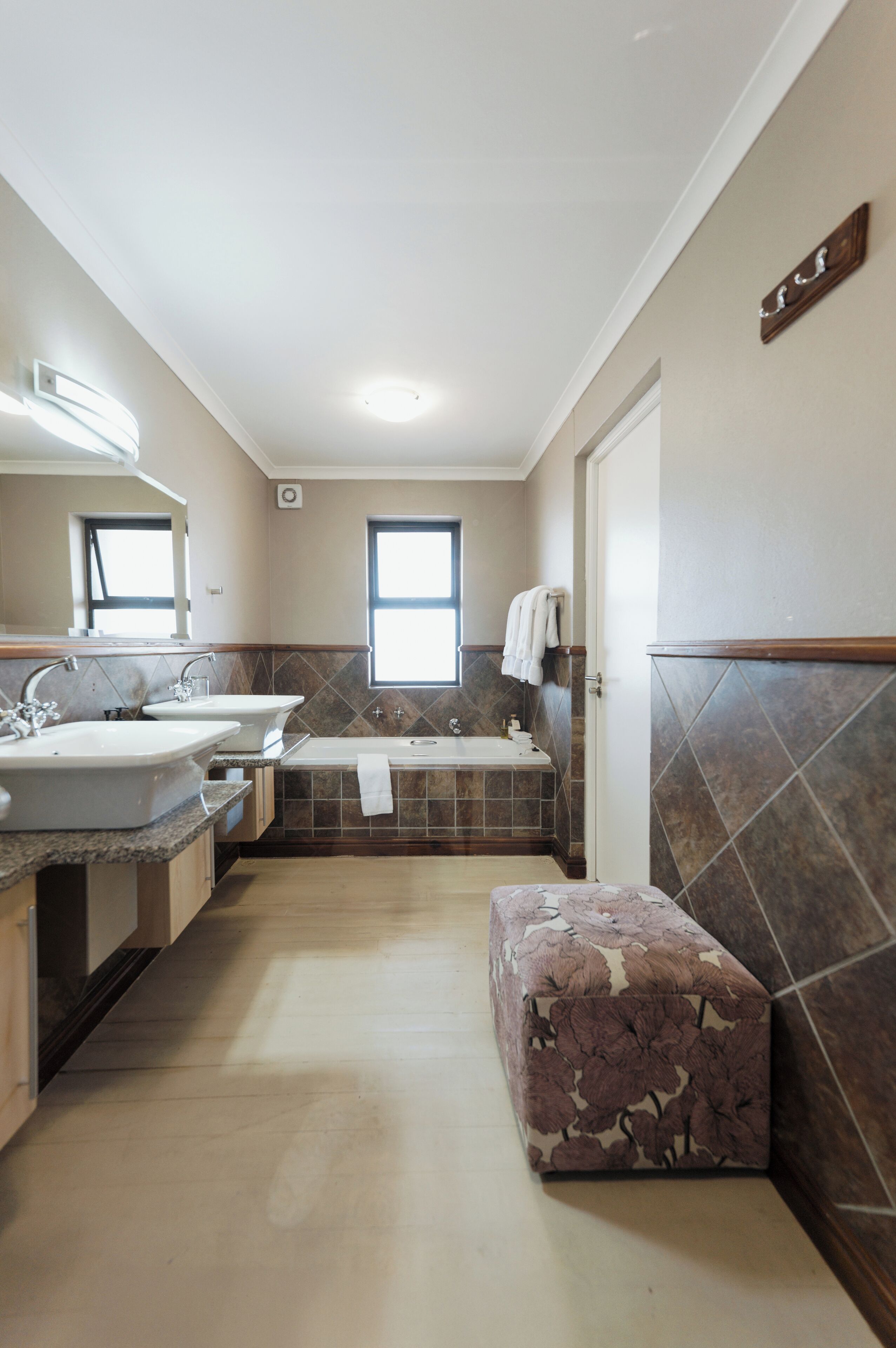 A bathroom with two sinks, a bathtub, and a window.