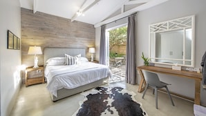 Un dormitorio con cama, lámparas de noche, escritorio con silla, espejo y alfombra de piel de vaca.