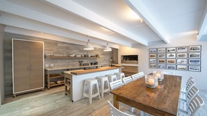 Una cocina moderna con una isla de madera, taburetes blancos y una mesa de comedor con velas.