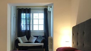 Une chambre à coucher avec un lit, une fenêtre avec des rideaux, un radiateur et une lampe de chevet.