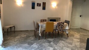 Un espace repas doté d’un sol en marbre, d’une table recouverte de nappes à motifs et d’appliques murales.