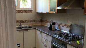 Une cuisine de taille réduite avec des meubles blancs, une cuisinière à gaz et un four encastré.