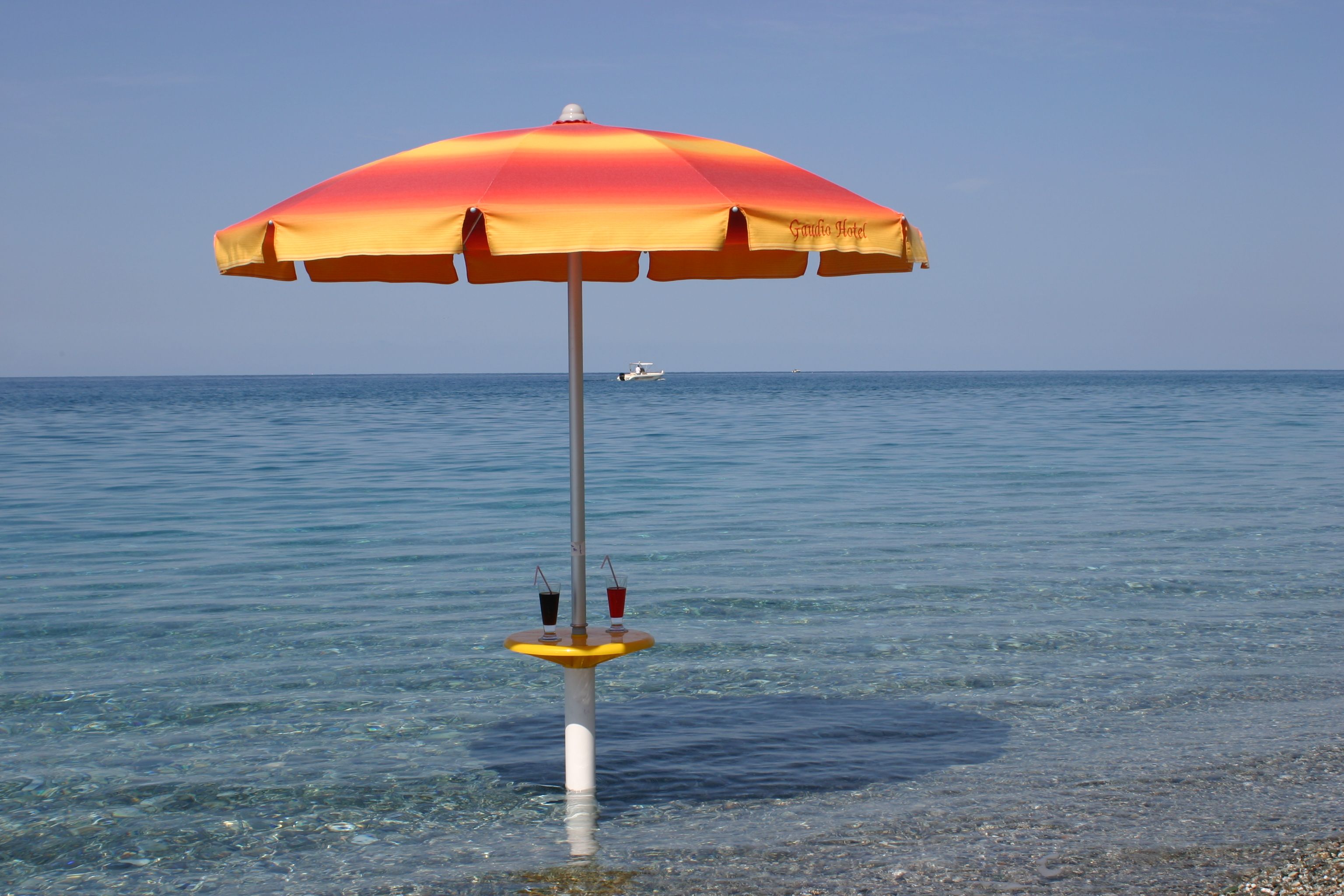 Una sombrilla de playa con vistas despejadas al mar y un barco a lo lejos.