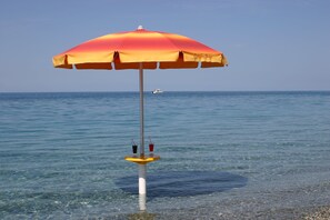Una sombrilla de playa con vistas despejadas al mar y un barco a lo lejos.