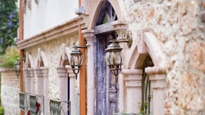 A building with a stone facade, a blue door, and wrought iron railings. - CavliHane 1885 (Ayvalik)