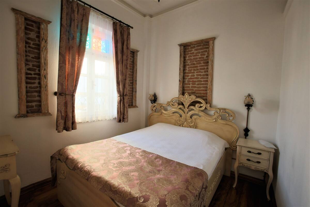 A bedroom with a bed, a nightstand, a lamp, and a window with curtains.