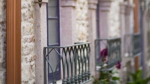 A stone building with a balcony, a wrought iron railing, and a hanging lantern. - CavliHane 1885 (Ayvalik)