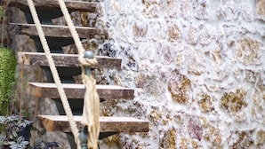 A stone wall with a wooden staircase and a rope ladder. - CavliHane 1885 (Ayvalik)