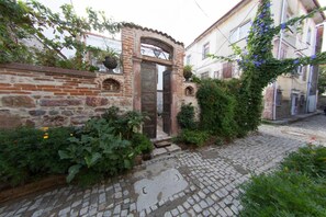 A cobblestone pathway leading to a rustic brick entrance with a wooden door. - CavliHane 1885 (Ayvalik)