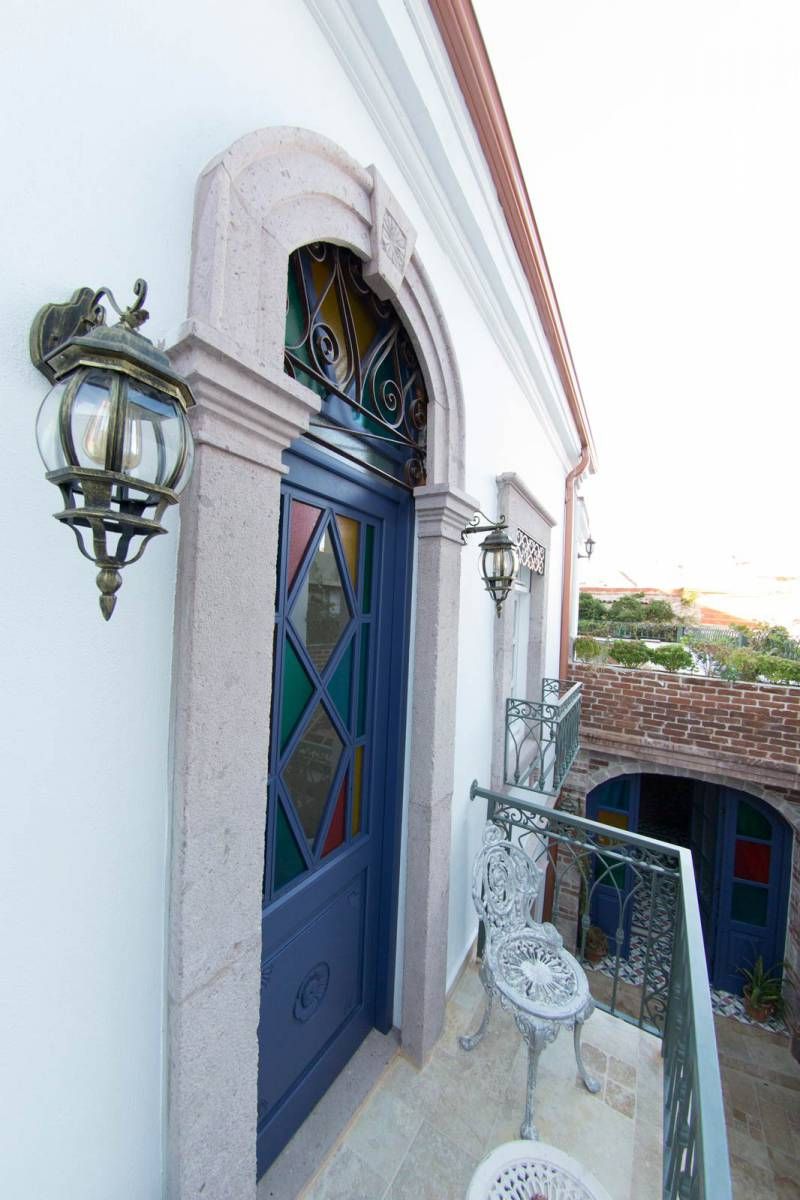 A balcony with a blue door, a white chair, and a wrought iron railing.