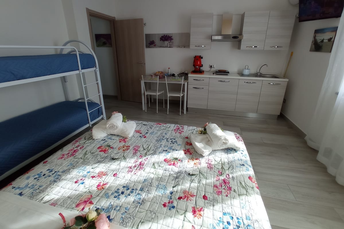 Pieni huone, jossa on kerrossängyt, pieni keittiö ja ruokailutila.