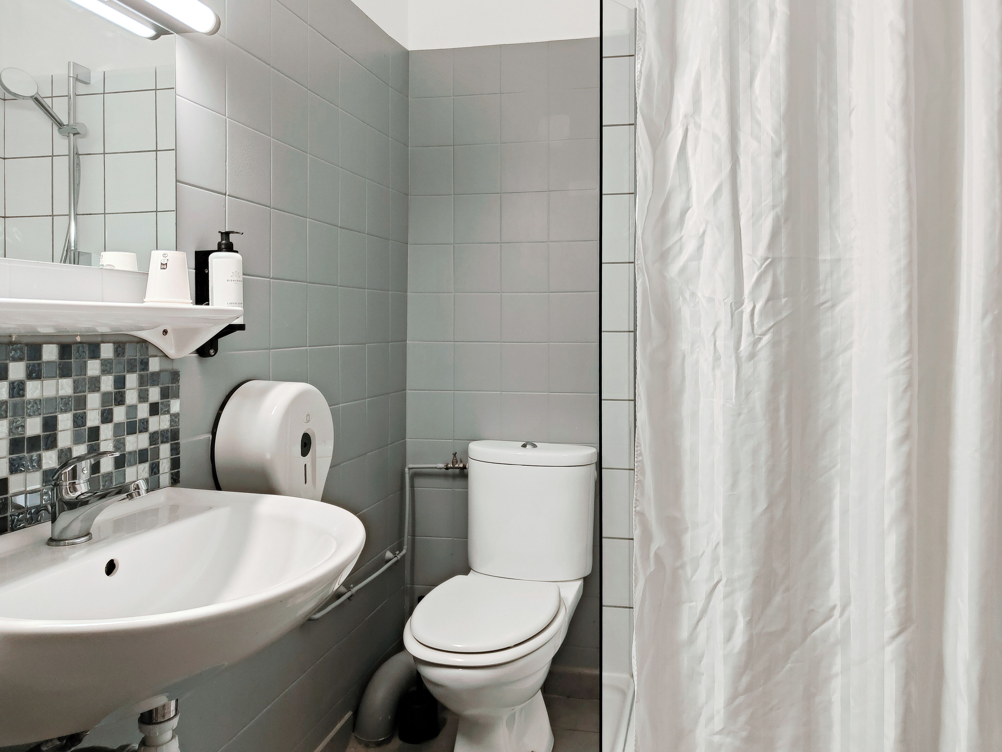 A modern bathroom with a white sink, toilet, and shower curtain.
