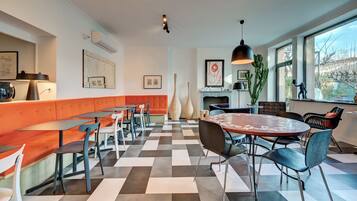 Un café moderno con suelo a cuadros, asientos acolchados color naranja y un amplio ventanal con vistas al exterior.