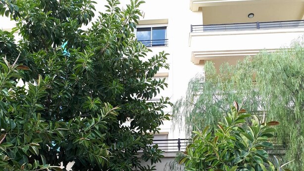 Ein Gebäude mit sandfarbener Fassade, einem zentralen Rundbogen und einem kleinen Balkon im oberen Geschoss.