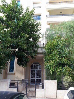 A building with a beige facade, a central arched entrance, and a small balcony on the upper floor. - Cosy Apartment Tanit Center (La Marsa)