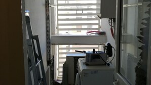Eine kleine Küche mit einem Kühlschrank, einer Spüle und einem Fenster mit Jalousien.