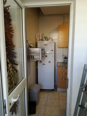 A compact kitchen with a refrigerator, microwave, and wooden cabinets. - Cosy Apartment Tanit Center (La Marsa)