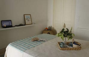 A neatly arranged bedroom with a bed, a laptop on a shelf, a framed picture, a plant, and a tray with cups and a book. - La Chambre Verte (Sidi Bou Said)