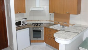 A compact kitchen with a gas stove, oven, microwave, and a sink.