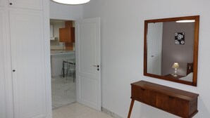 A hallway with a wooden console table, a mirror, and a door leading to a kitchen area.