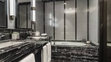 Un baño moderno con un espejo grande, encimeras de mármol negro, una bañera y un inodoro.
