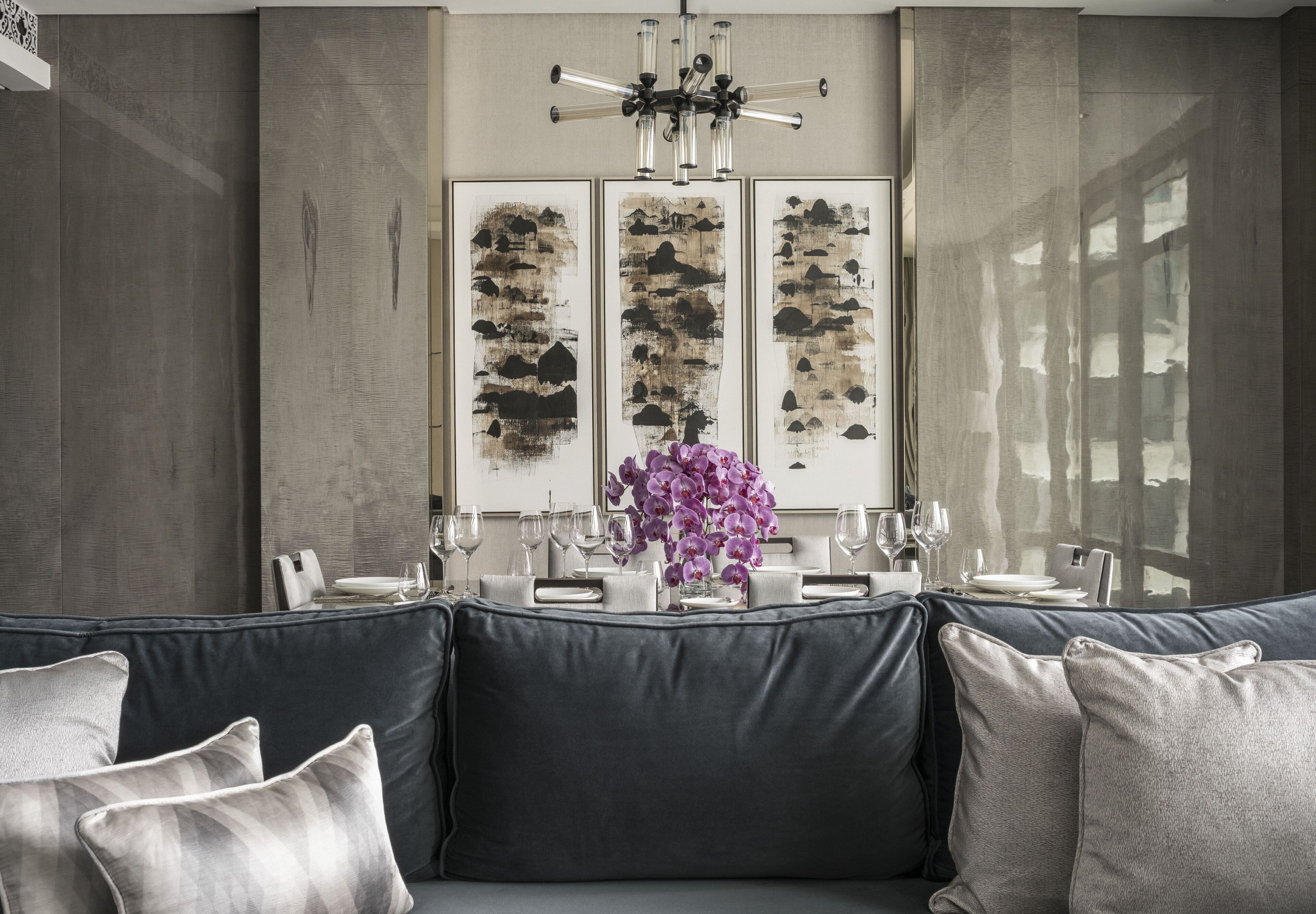 A modern dining area with a sofa, a table set for four, and abstract wall art.