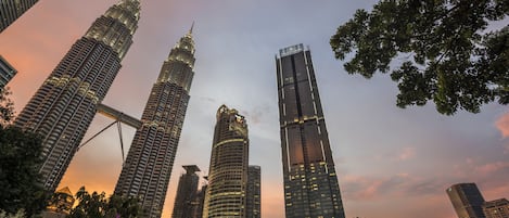 Un paisaje urbano con varios rascacielos, incluyendo las emblemáticas Torres Petronas, bajo un cielo crepuscular.