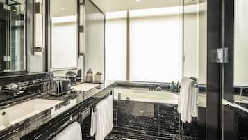 A modern bathroom with a large mirror, two sinks, a bathtub, and a glass shower enclosure.