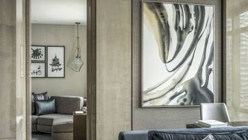 Een moderne woonkamer met een hoekbank, een bijzettafeltje en een groot abstract schilderij aan de muur.