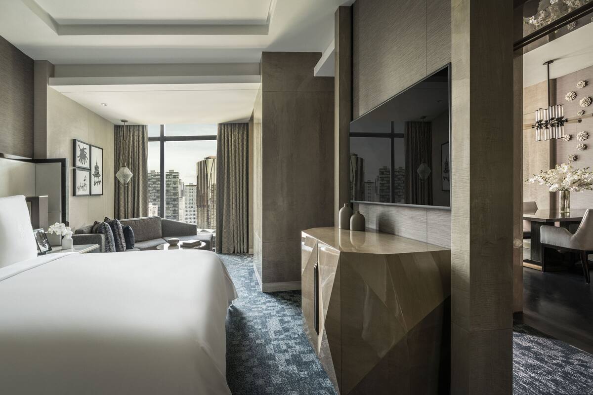 Une chambre d’hôtel moderne dotée d’un grand lit, d’un bureau et offrant une vue sur le panorama urbain.