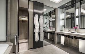 A modern bathroom with a large mirror, dual sinks, and a walk-in shower.