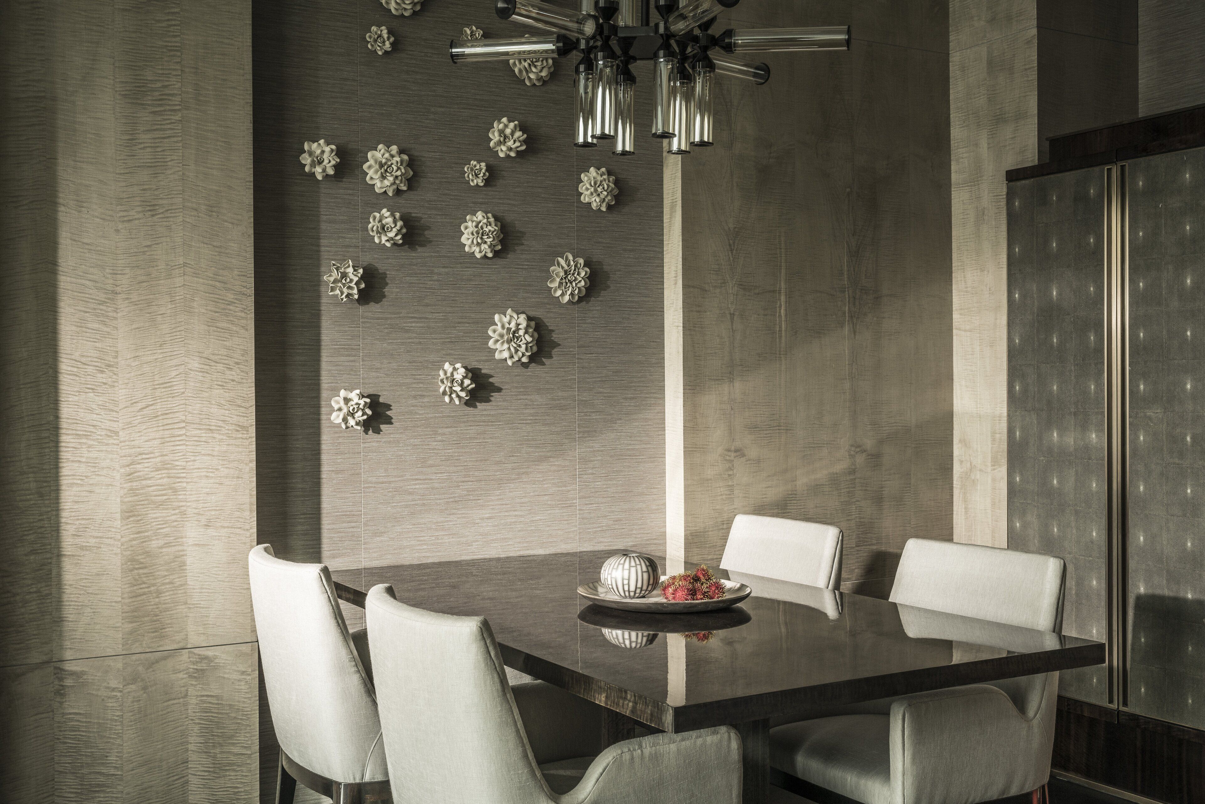 A modern dining area with a dark wooden table, white upholstered chairs, and decorative wall art.
