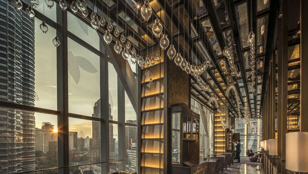 Un hall d’hôtel luxueux, situé dans un immeuble de grande hauteur, offrant une vue sur le paysage urbain, doté de grandes fenêtres et d’un mobilier moderne.