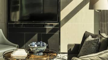 A modern living room with a sofa, a coffee table with a bowl of decorative eggs, and a flat-screen TV mounted on the wall.