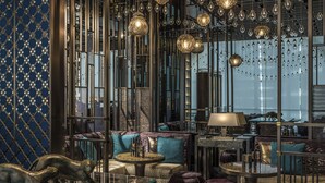 Un intérieur luxueux au design moderne, comprenant un espace salon avec des canapés et des poufs, une table basse en verre et une sculpture décorative.
