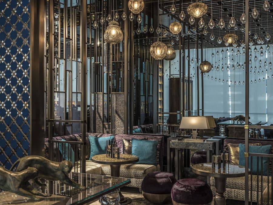 Un interior lujoso de diseño moderno, con una zona de estar que incluye sofás, otomanas, una mesa de centro de vidrio y una escultura decorativa.